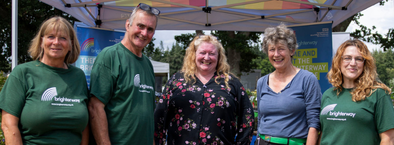 Brighterway Charity Manager Phil Pride and TV gardening celebrity Charlie Dimmock stand in front of the Brighterway stand with the Brighterway team at the 2025 New Forest Show.