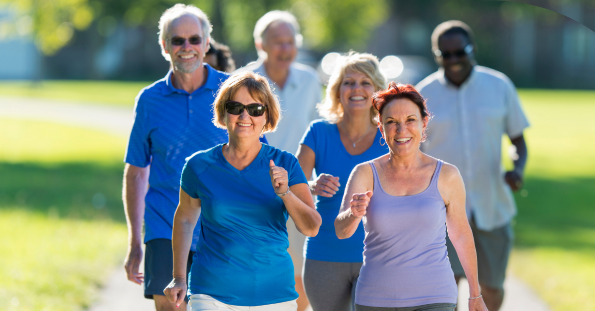 A group of 6 people in a step-a-thon, 3 men and 3 women, walk towards the camera smiling. They are middle aged and dressed in blues and purples.